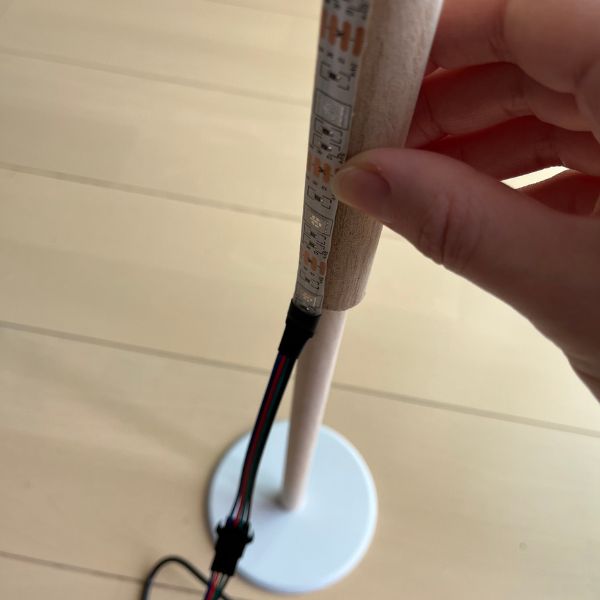テープライトを貼り付けた丸棒をキッチンペーパーホルダーに固定する様子